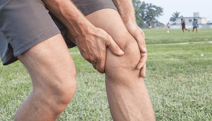 мужчина держится за колено